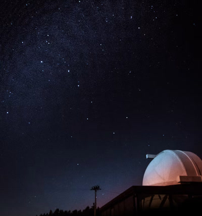 An observatory dome beneath a star-filled night sky.